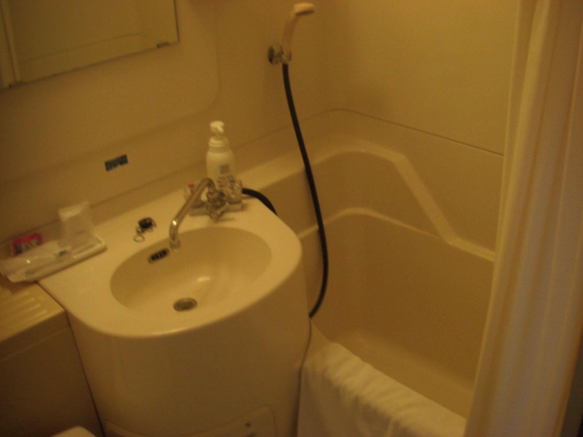 Un baño con lavamanos, grifo y cabezal de ducha.