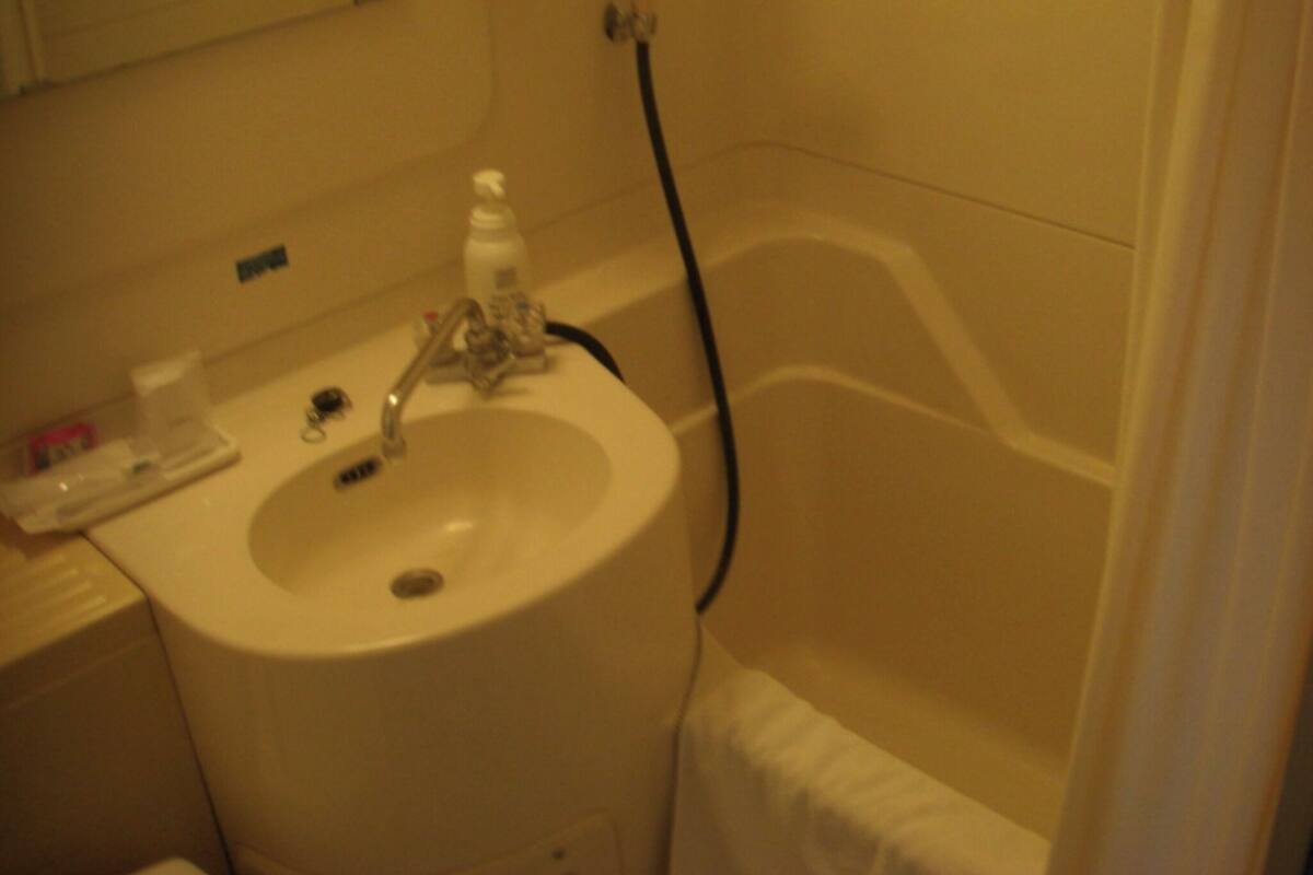 Un baño con lavamanos, grifo y cabezal de ducha.