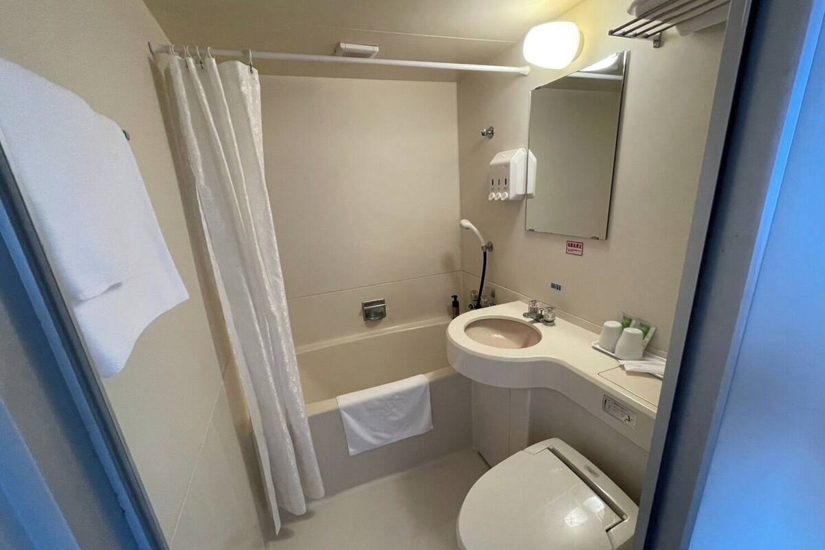 A bathroom with a toilet, sink, and shower area.