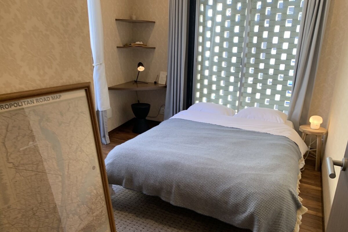 A bedroom with a bed, a map on the wall, and a window with blinds.