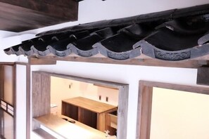A traditional Japanese-style interior with a wooden ceiling and a view into a room with a wooden counter and sink. - Teramachiya Fushin An (Kanazawa)