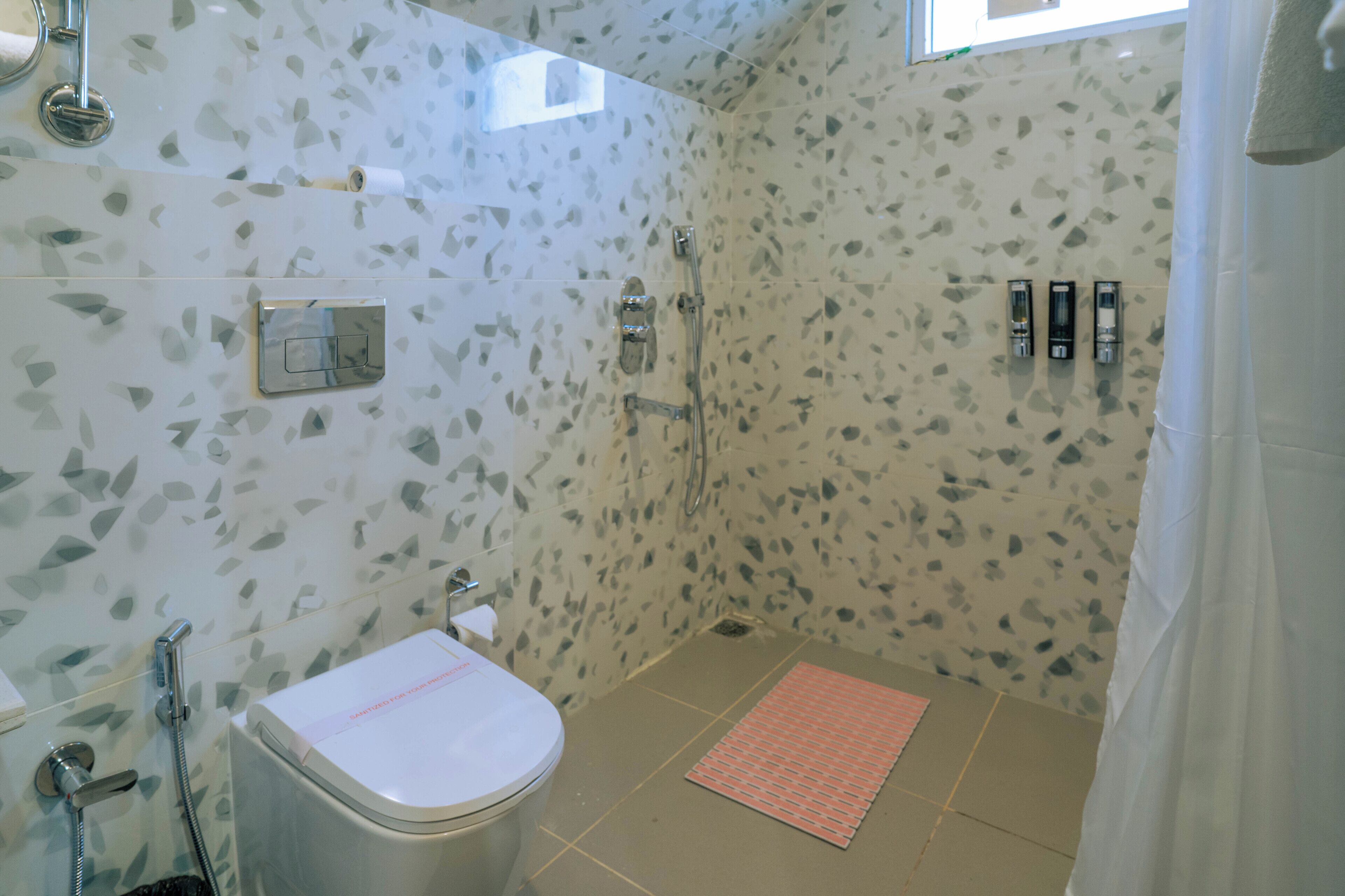 Un baño con inodoro, ducha y una pequeña ventana.