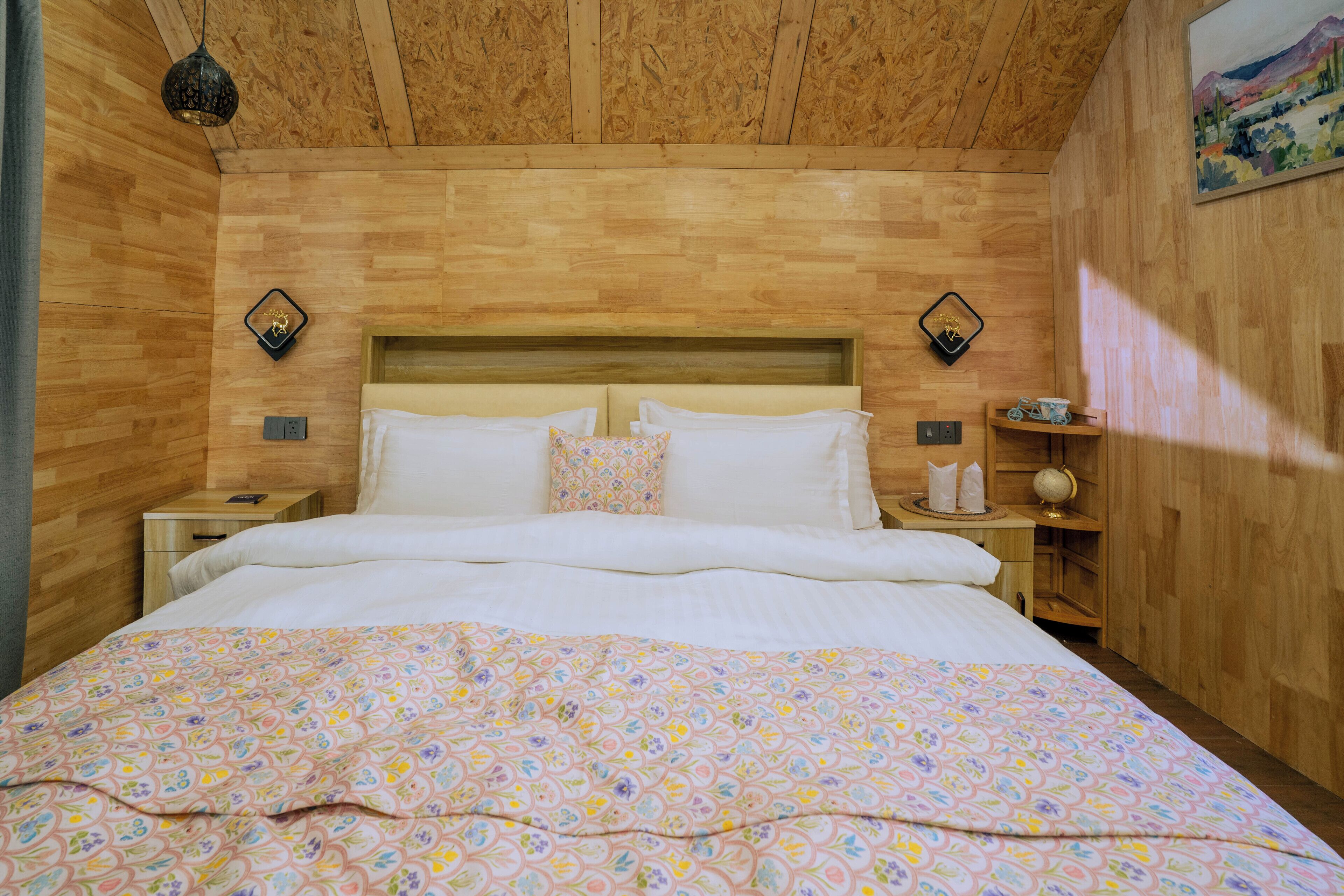 A wooden-paneled bedroom with a bed, nightstands, and a wall-mounted shelf.