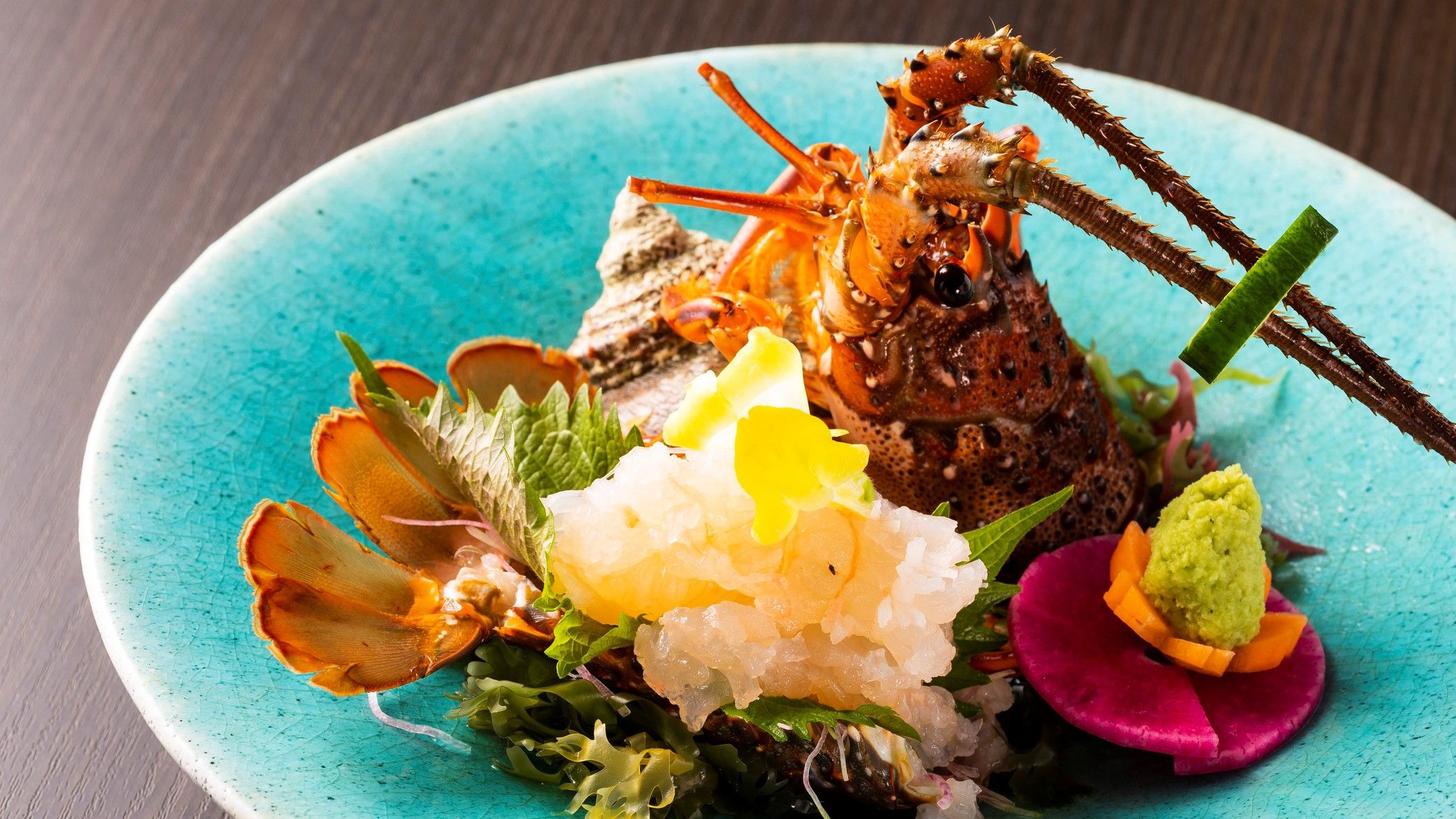 A seafood dish with a lobster tail, garnishes, and a blue plate.