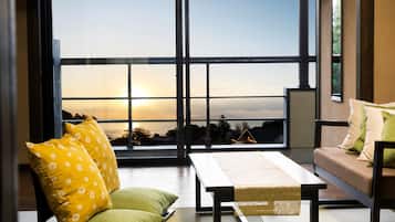 A modern living room with a large window, a sofa, a table, and decorative pillows.