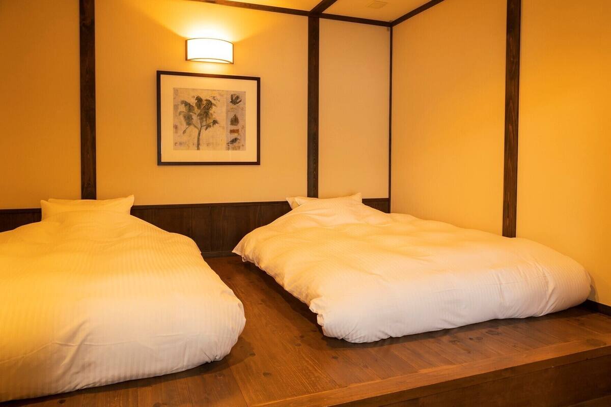 Two single beds with wooden headboards and a framed artwork above them.