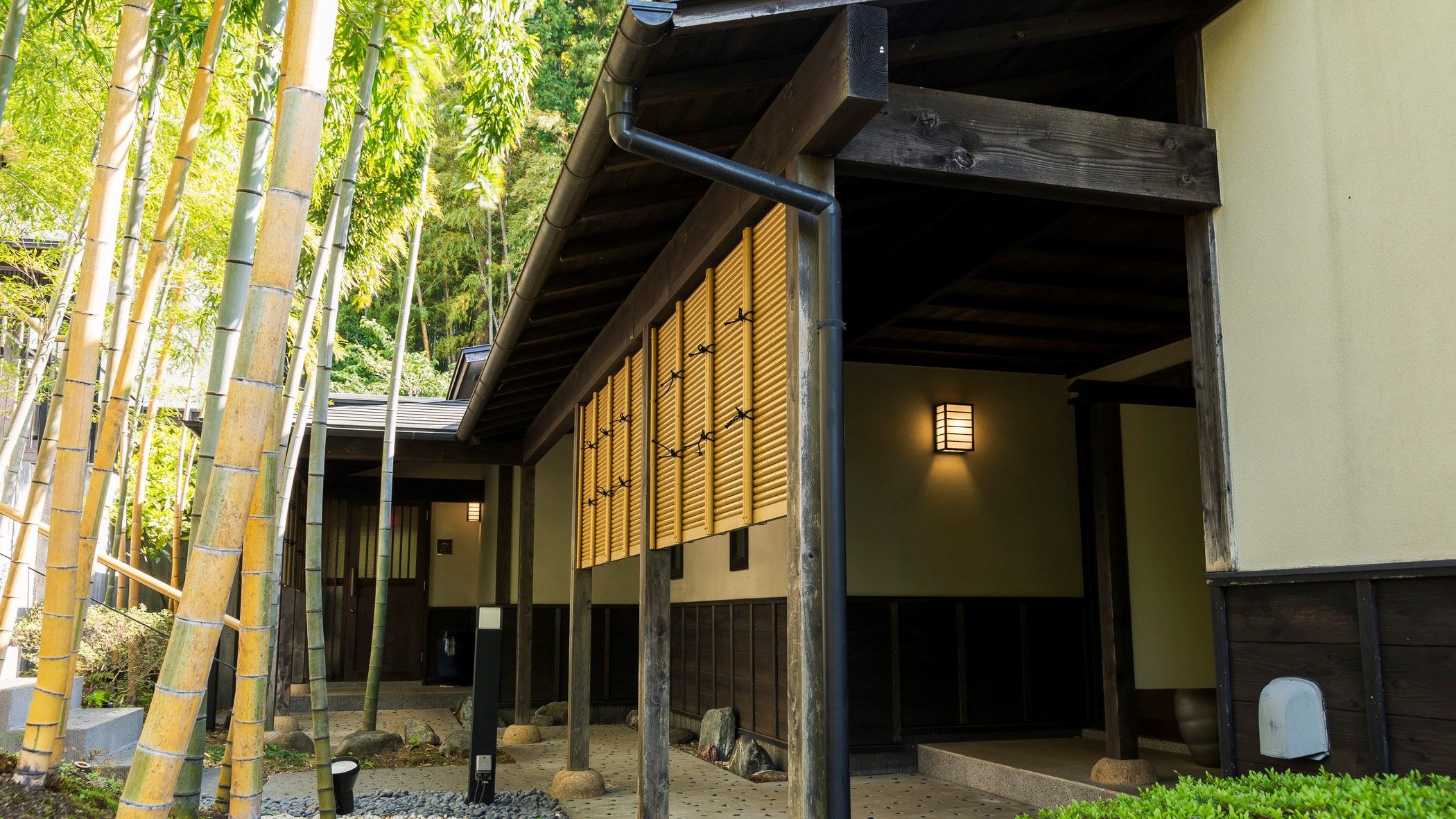 A traditional Japanese building with a covered walkway, bamboo trees, and a lantern.
