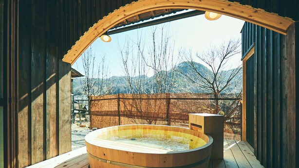 A wooden hot tub on a deck with a view of mountains and a wooden fence. - Kominka Yado Loof Kyonoie (Hokuto)