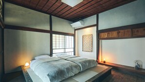 A traditional Japanese-style room with tatami flooring, a low platform bed, shoji screens, and a wooden ceiling. - Kominka Yado Loof Kyonoie (Hokuto)