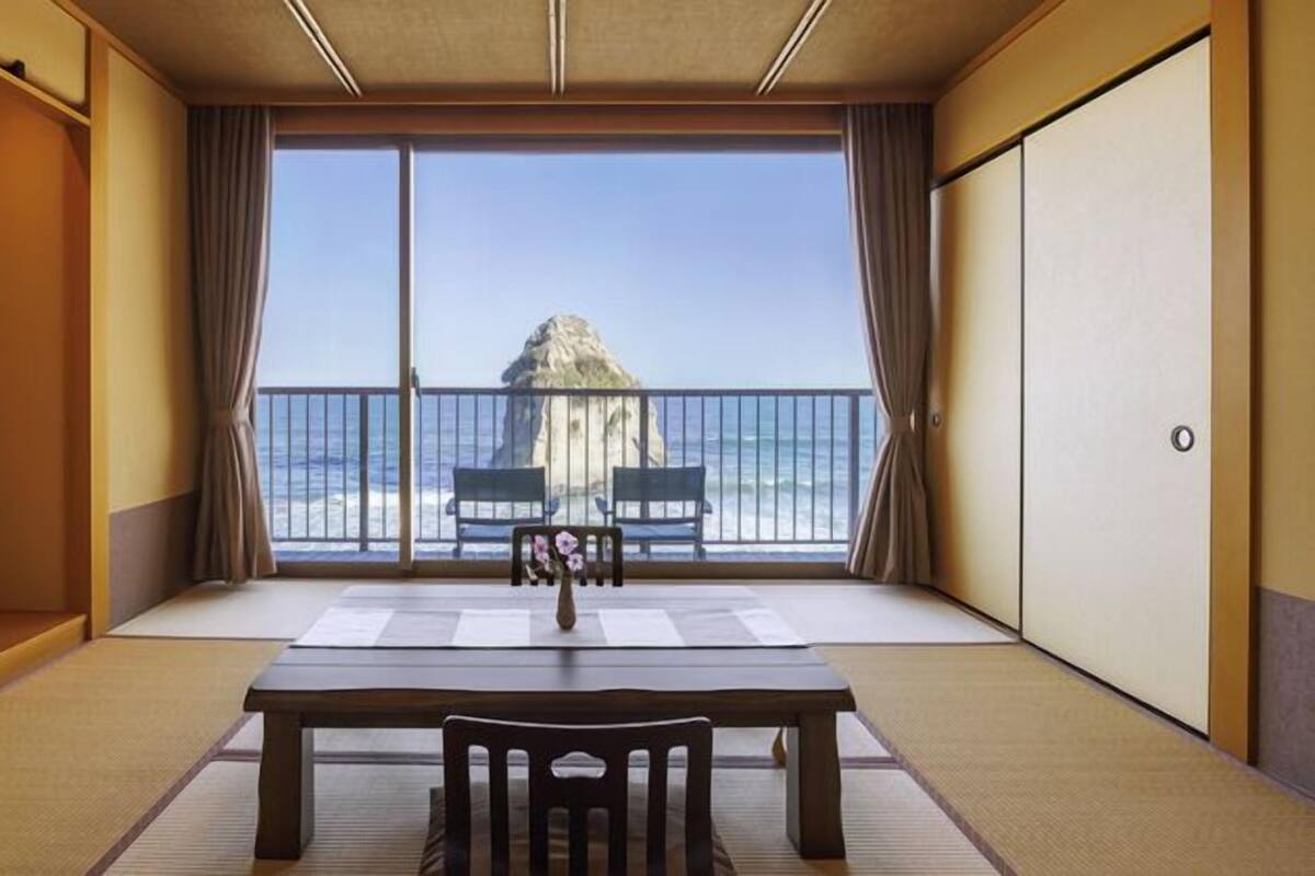 Una habitación con suelo de tatami, una mesa baja y vista al mar.
