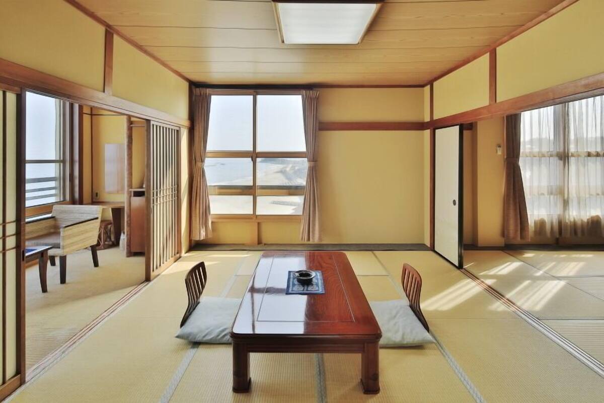 Una habitación japonesa tradicional con suelo de tatami, una mesa de madera baja y puertas correderas.