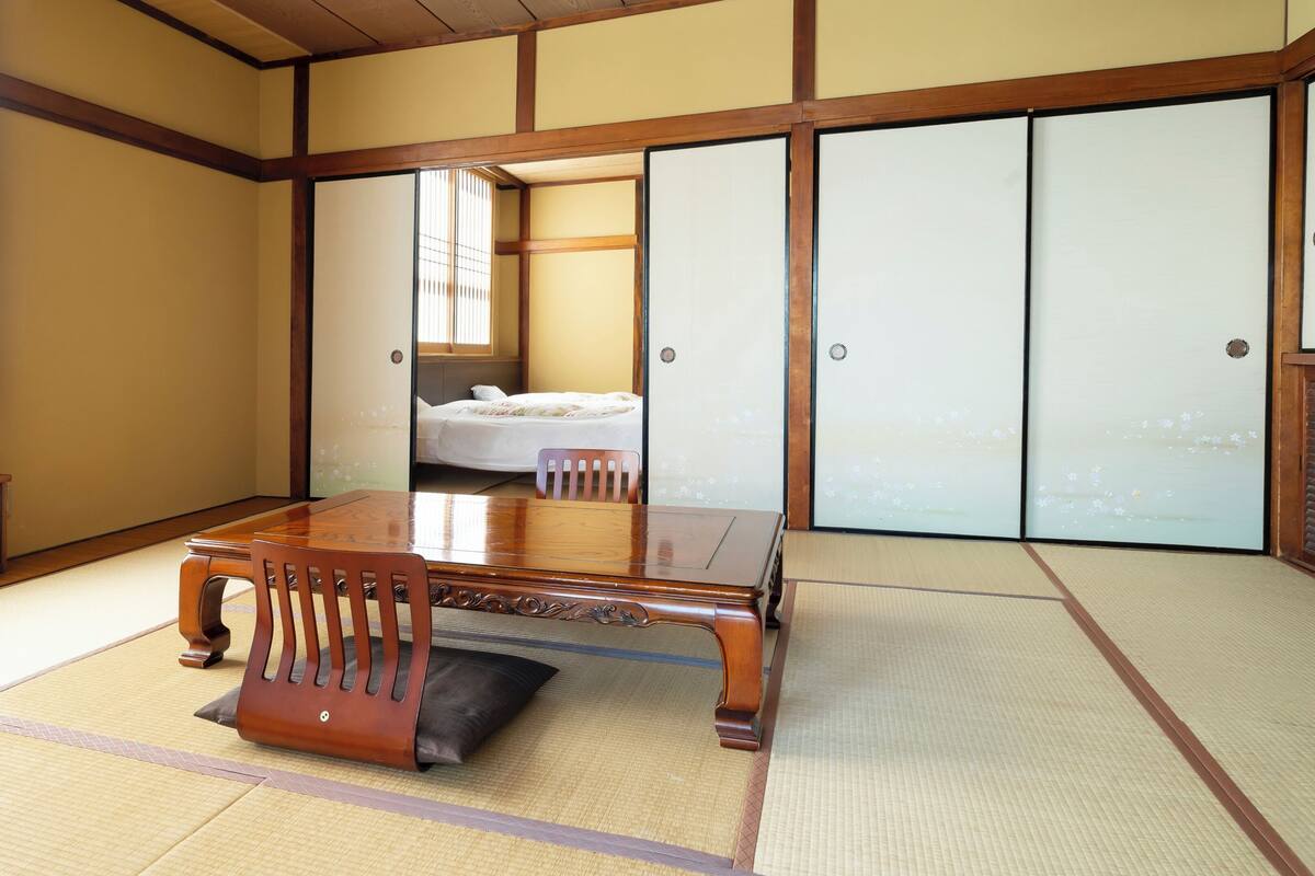Una habitación japonesa tradicional con suelo de tatami, una mesa de madera y puertas correderas.