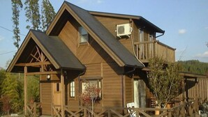 A wooden cabin with a balcony, a covered porch, and a stone pathway. - Hiiragi Cottage (Hita)