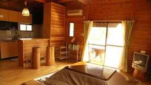 A wooden cabin interior with a kitchen, dining area, and a large window with curtains. - Hiiragi Cottage (Hita)