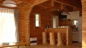 A wooden interior with a tatami mat, a kitchen area, and a dining table. - Hiiragi Cottage (Hita)