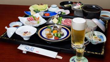 A tray with various food items, a mug of beer, and a teapot on a table.
