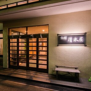 A building entrance with a large glass door, a bench outside, and a sign with Chinese characters. - Nasuyumoto Onsen Ryokan Shimizuya (Nasu)