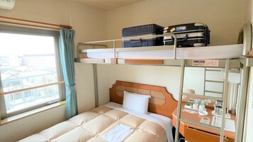 Habitación con literas, una ventana, un escritorio con espejo y una maleta en la litera superior.