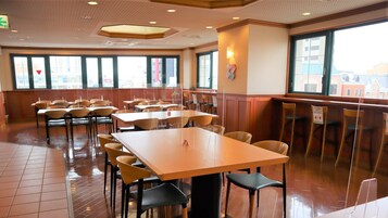 Un comedor amplio con varias mesas y sillas, ventanas grandes y un interior moderno y limpio.