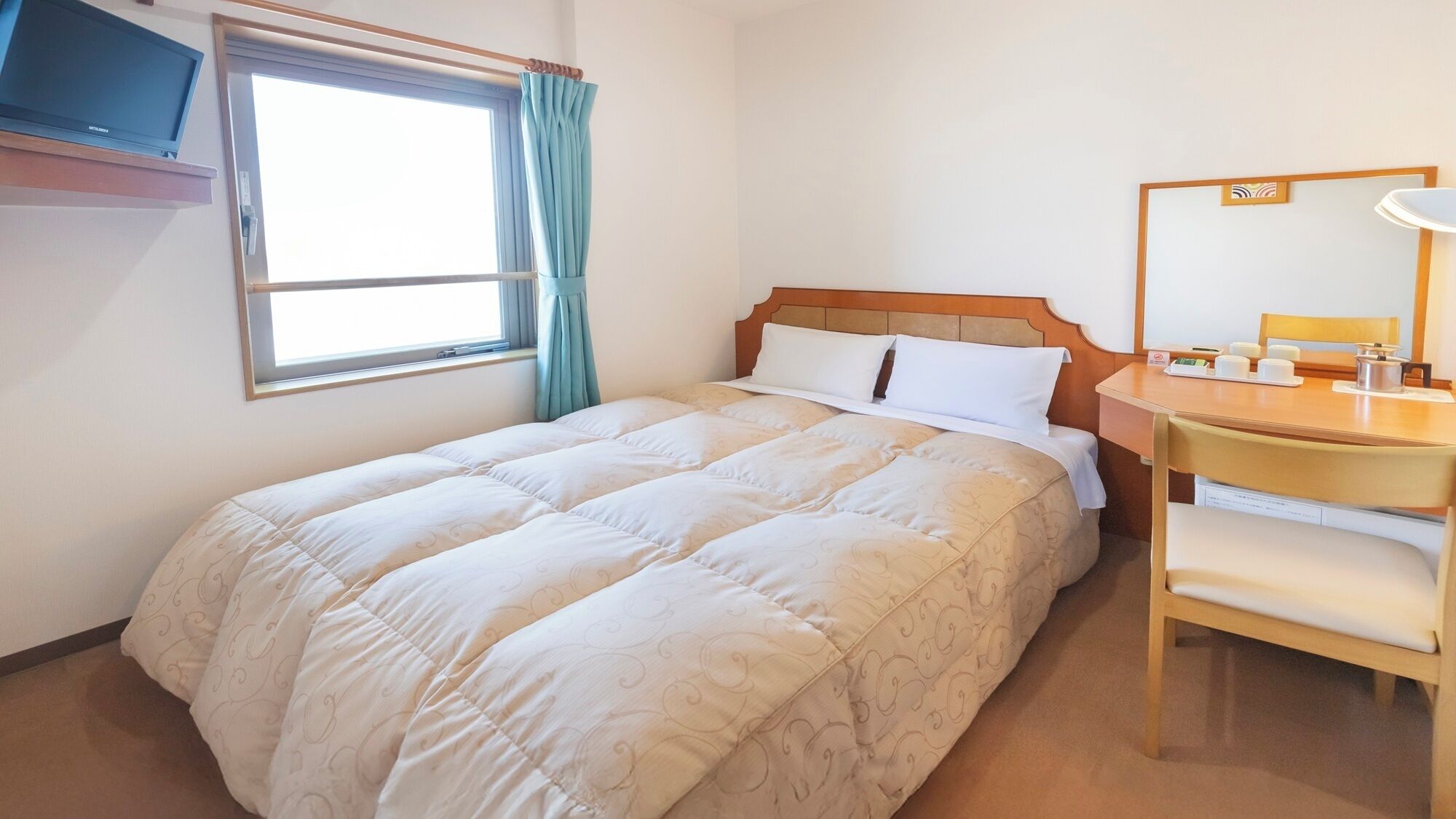 Une chambre d’hôtel équipée d’un lit, d’un bureau, d’une chaise, d’une télévision et d’une fenêtre avec des rideaux.