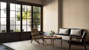 Een moderne kamer met een groot raam, een bank, twee stoelen en een kleine tafel met een plant.