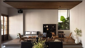 Een moderne woonkamer met een bank, stoelen, een salontafel en een boekenkast.
