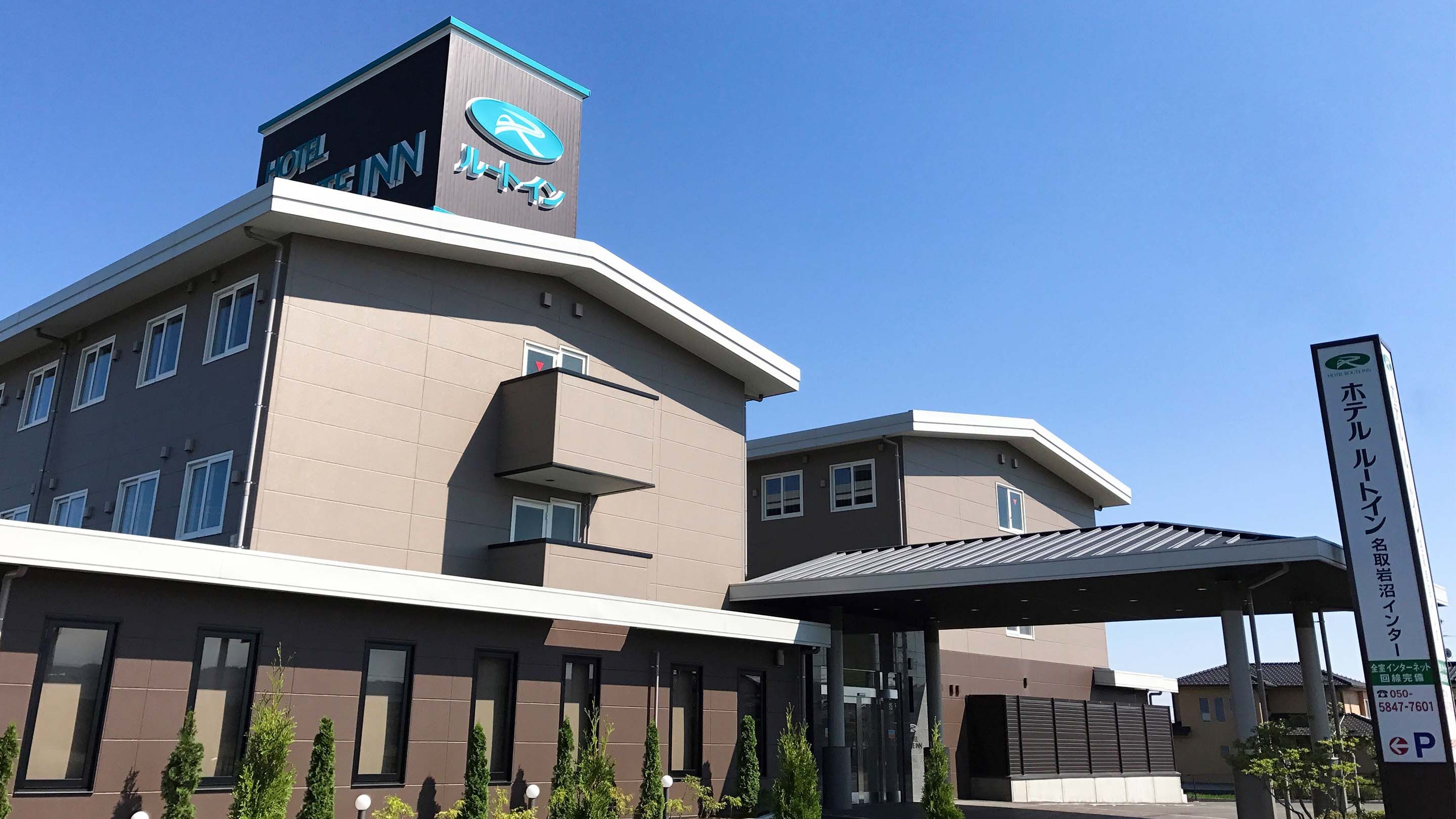 A hotel with a modern design, featuring a prominent logo on the facade, a covered entrance, and a clear sky above.