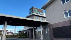 A hotel entrance with a covered walkway, a sign reading 'Hotel Route Inn,' and a modern building facade. - Hotel Route-inn Natori Iwanuma Inter (Iwanuma)