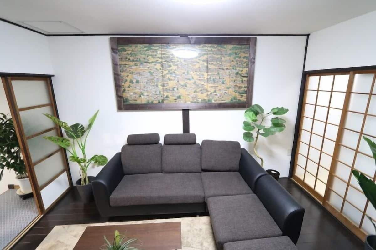 A room with a sectional sofa, a tatami mat floor, a shoji screen, and a large map on the wall.