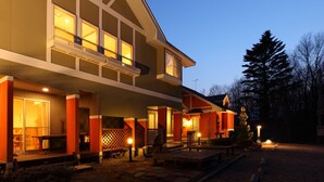 A modern two-story house with a covered patio area, large windows, and a well-lit exterior at dusk. - Pension Twilight (Nasu)