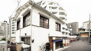 A multi-story residential building with balconies, a parked scooter, and a gated entrance. - Araiya (Tokyo)