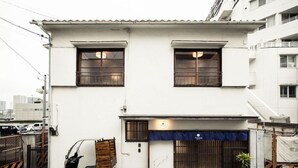 A two-story building with a white facade, a gated entrance, and a parked scooter. - Araiya (Tokyo)