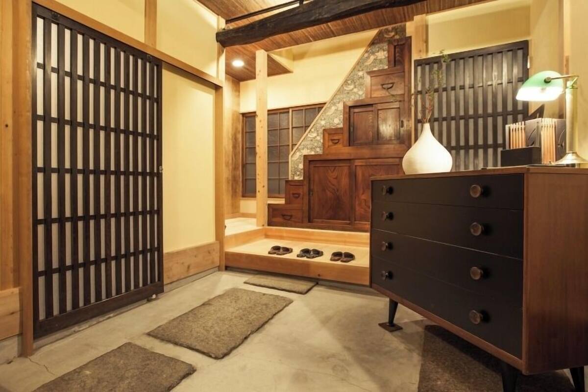 Ein traditionelles japanisches Interieur mit Tatami-Böden, einer Schiebetür, einer Treppe und einer Kommode mit Schubladen.