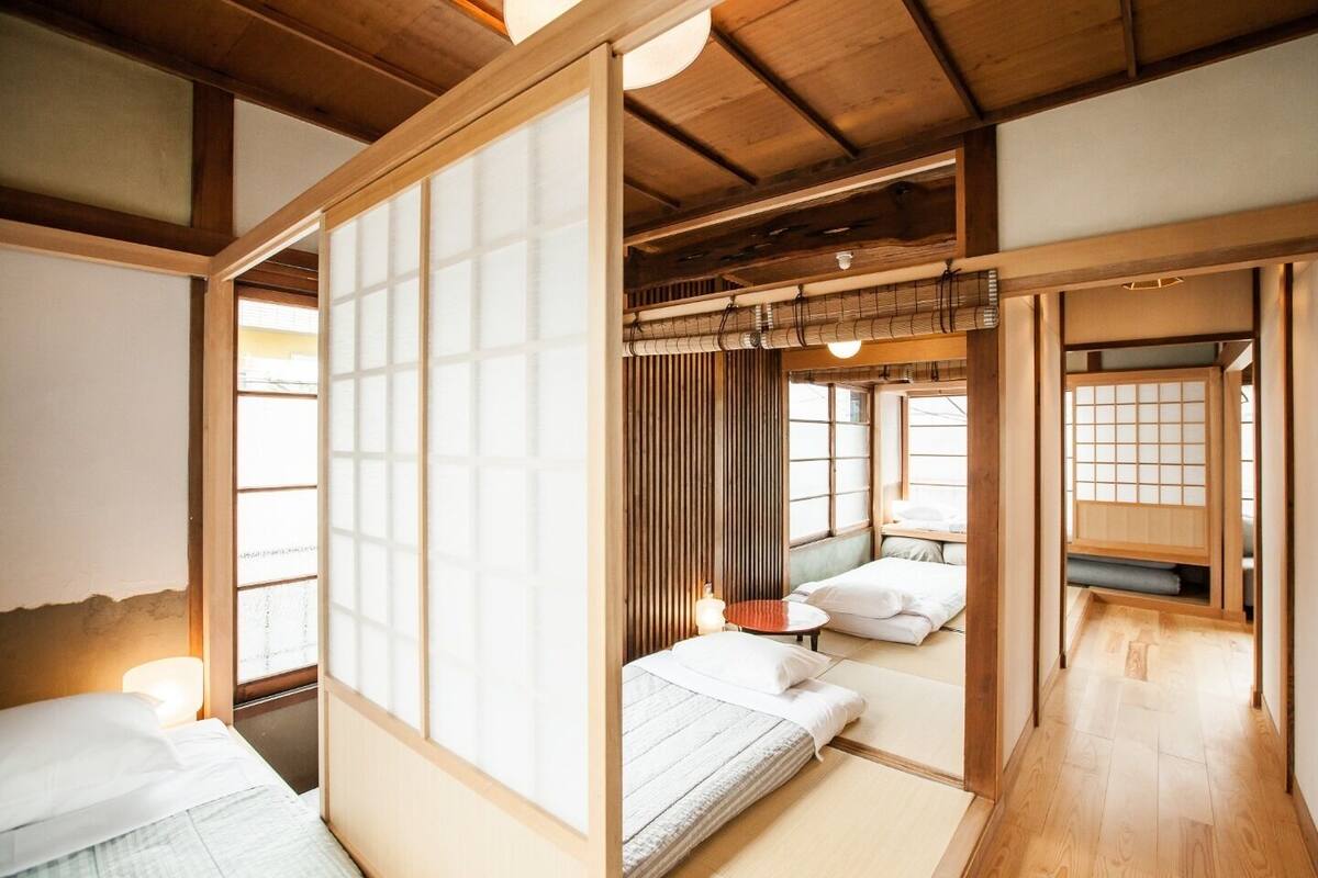 Ein traditioneller japanischer Raum mit Tatami-Boden, Schiebetüren und einer niedrigen Decke.