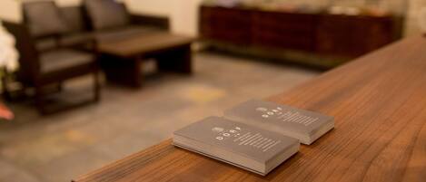 A stack of business cards on a wooden table in a room with a sofa and a bookshelf.
