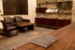 A stack of business cards on a wooden table in a room with a sofa and a bookshelf. - Tassel Inn Kyoto Kawaramachi Nijo (Kyoto)
