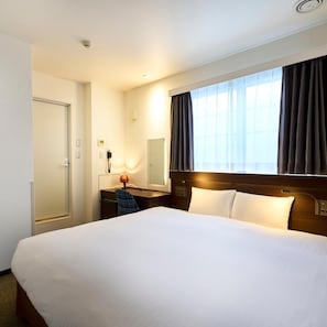 A hotel room with a large bed, a desk with a lamp, a telephone, and a window with curtains. - Tassel Inn Kyoto Kawaramachi Nijo (Kyoto)