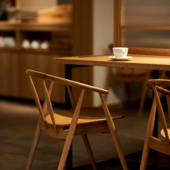 A wooden chair and table in a room with a warm ambiance. - Tassel Inn Kyoto Kawaramachi Nijo (Kyoto)
