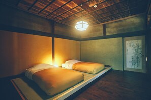 Ein Zimmer mit zwei Betten, einer Holzbalkendecke und einem gerahmten Kunstwerk an der Wand.