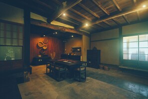 Une pièce de style japonais traditionnel, avec un sol recouvert de tatamis, une table basse avec des coussins et une porte coulissante.