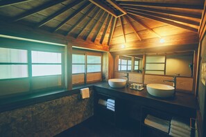 Ein Badezimmer mit Holzboden, zwei Waschbecken und großen Fenstern.