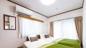A hotel room with a bed, a wooden bench, an air conditioning unit, a mirror, and curtains. - Sea Stay Okinawa (Onna)