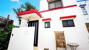 A building with a white facade, red accents, and a sign reading "SEA STAY OKINAWA". - Sea Stay Okinawa (Onna)