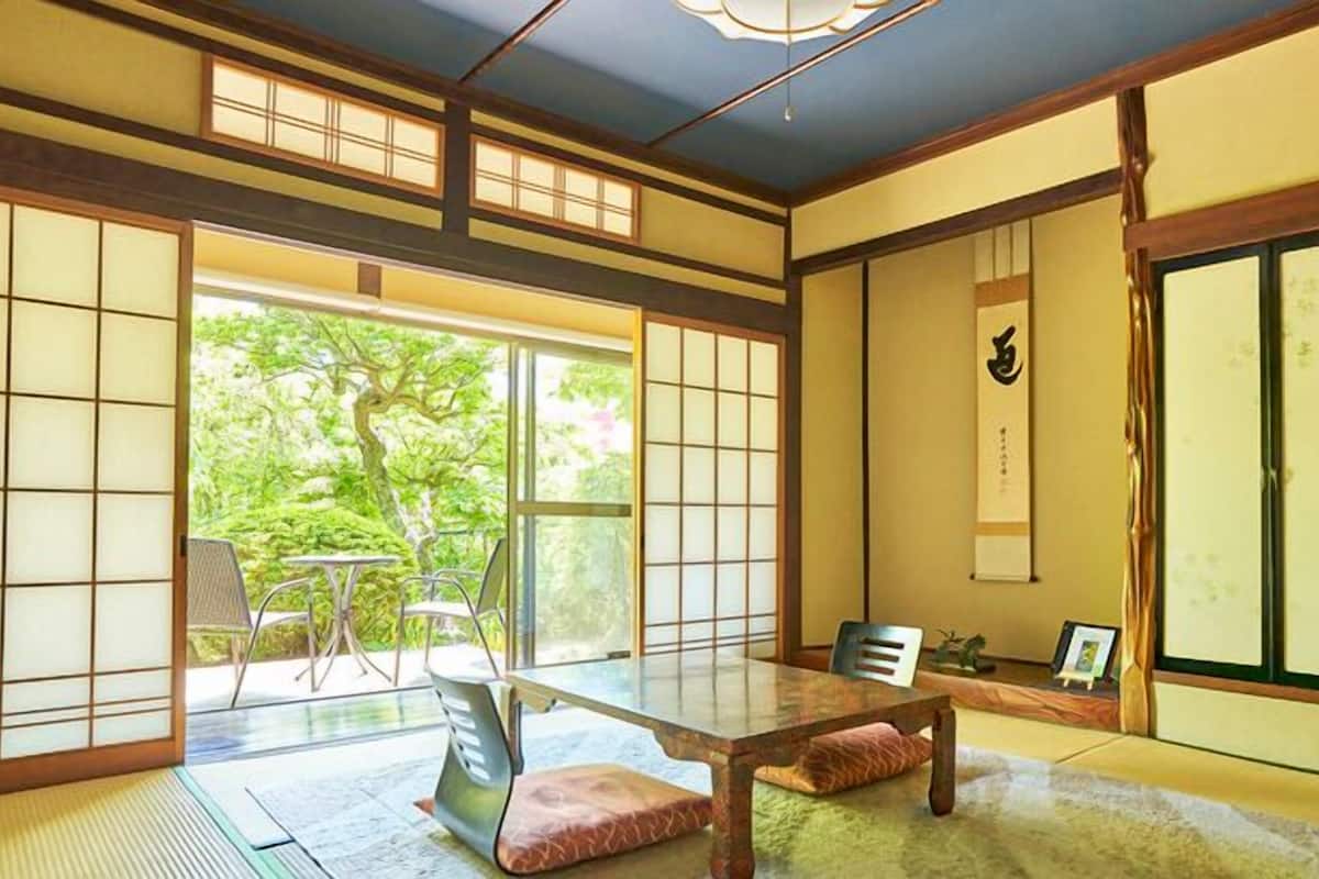 Une pièce de style japonais traditionnel, avec un sol recouvert de tatamis, des portes coulissantes et une petite table basse entourée de coussins.
