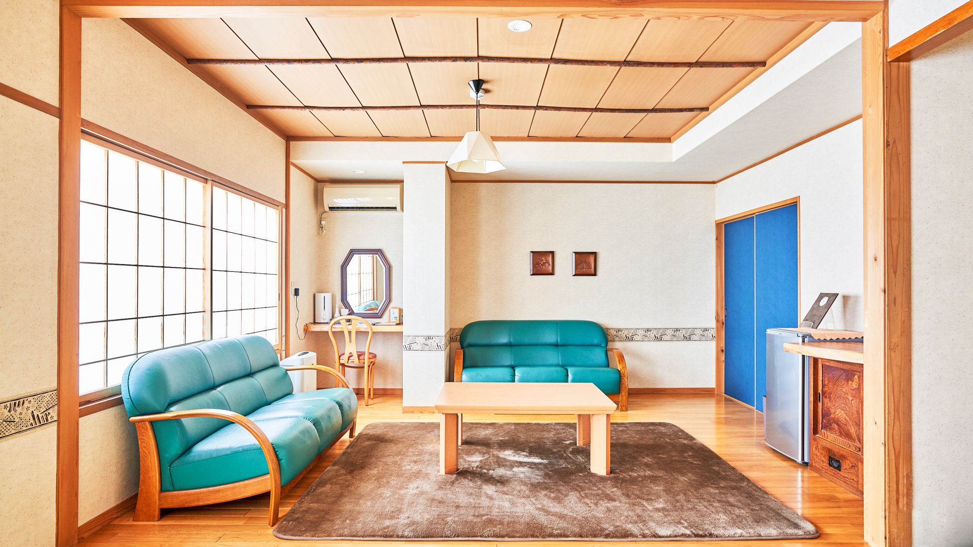 A room with a wooden ceiling, a sofa, a table, a mirror, and a cabinet.