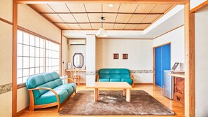 A room with a wooden ceiling, a sofa, a table, a mirror, and a cabinet. - Ueda Onsen Hotel Shoen (Ueda)