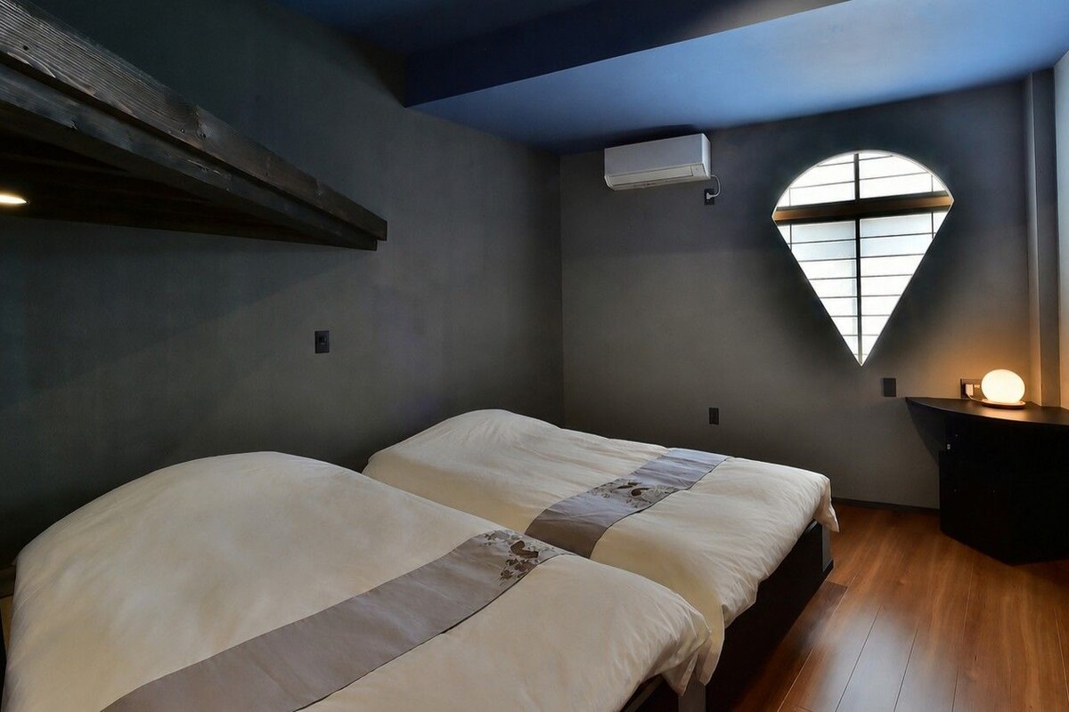 Un dormitorio con dos camas, una ventana con vistas y una mesita de noche con lámpara.