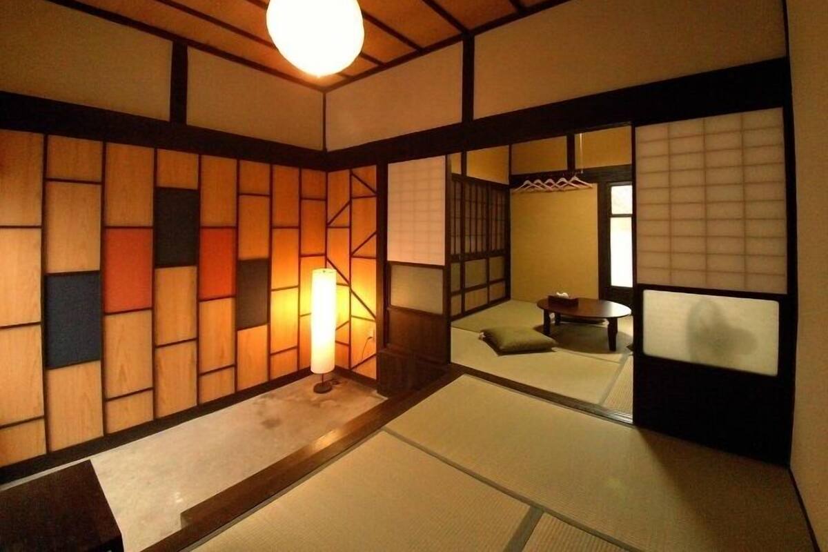 A traditional Japanese room with tatami flooring, a low table, and sliding doors.