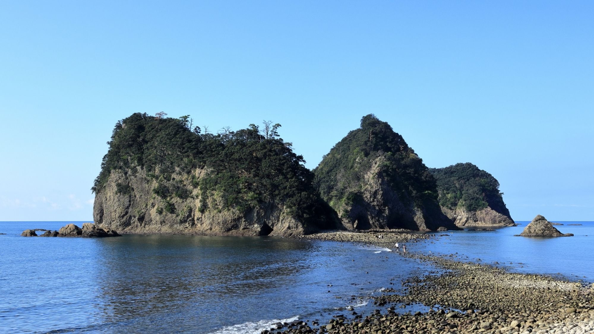 A coastal landscape with rocky formations and clear blue water.