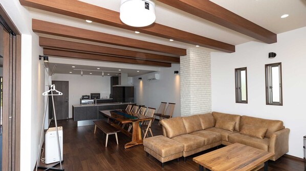 Un salon moderne avec un plafond en bois, un canapé, une table basse et un coin repas comprenant des chaises et une table.